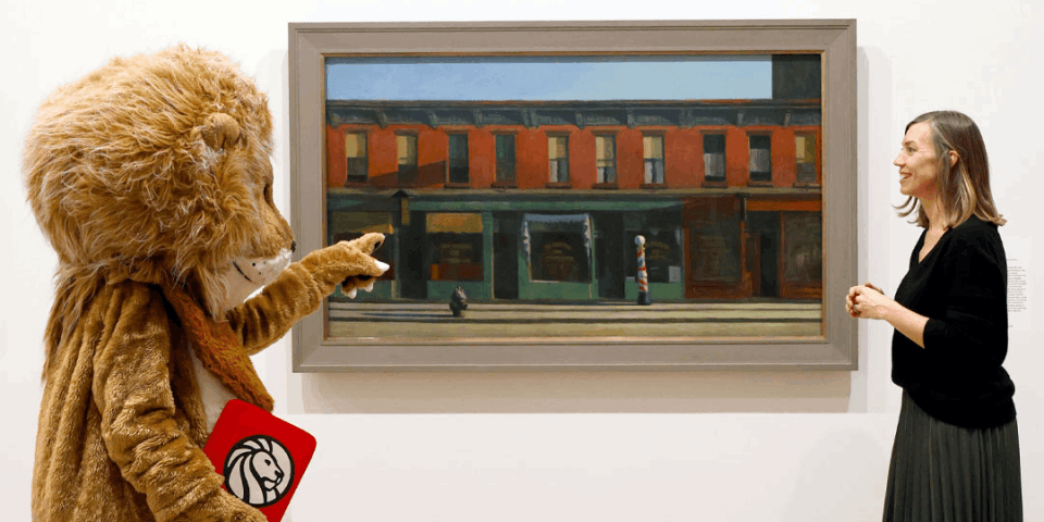 lion mascot and a museum curator stand looking at a painting together
