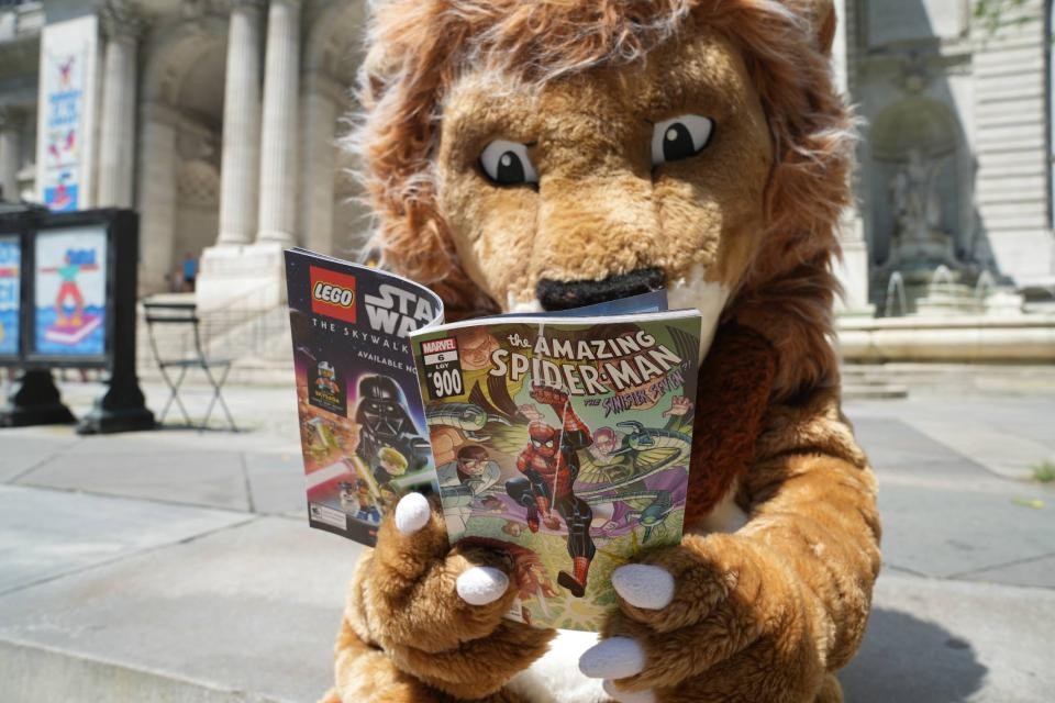 Patience the lion reading a Spider-Man comic on steps of The New York Public Library