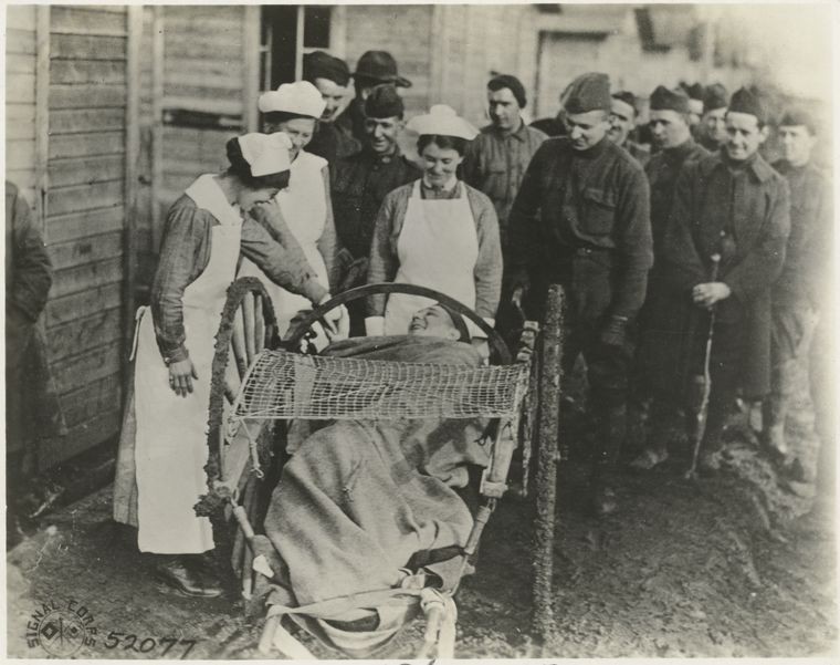 three nurses speaking to a main lying down in a makeshift gurney