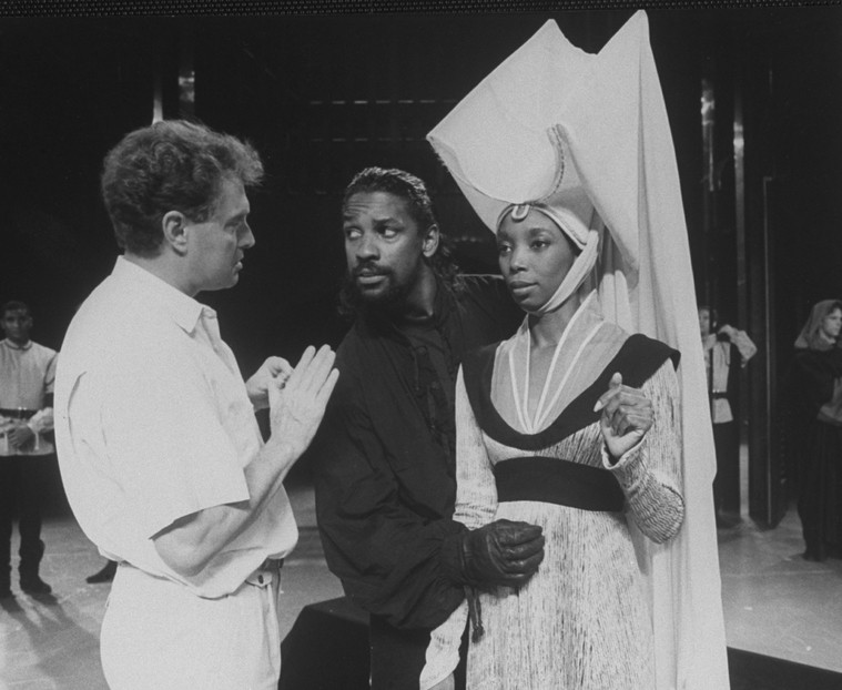 two actors in costume listen to a director speaking