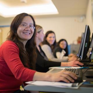 A library patron smiles toward camera while using a computer.