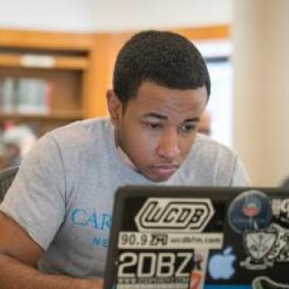 Young man working on laptop in library.