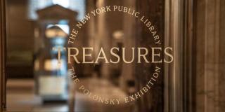 Photo of a glass door with a gold logo that reads: Treasures, The New York Public Library, The Polonsky Exhibition.