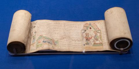 A historic scroll displaying an illuminated manuscript. 